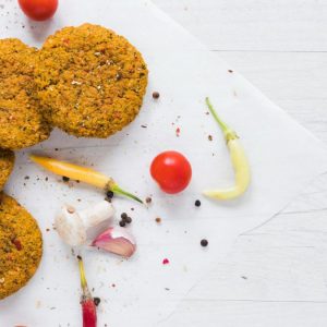 Burger vegetariani su sfondo chiaro con spezie e verdure estive. Ricetta antispreco estiva con legumi, dalla cucina ciociara.