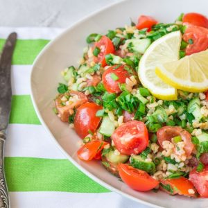 Tabbouleh freddo con farro, legumi misti, pomodorini e menta su sfondo rustico. Ricetta antispreco estiva della cucina ciociara.