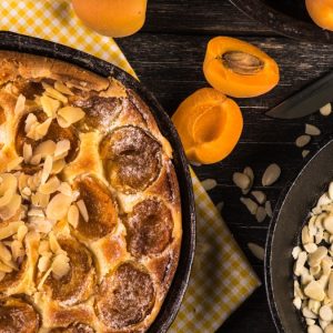 Crostata dorata con albicocche fresche e mandorle a lamelle, servita su piatto estivo