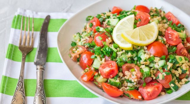 Tabbouleh freddo con farro, legumi misti, pomodorini e menta su sfondo rustico. Ricetta antispreco estiva della cucina ciociara.